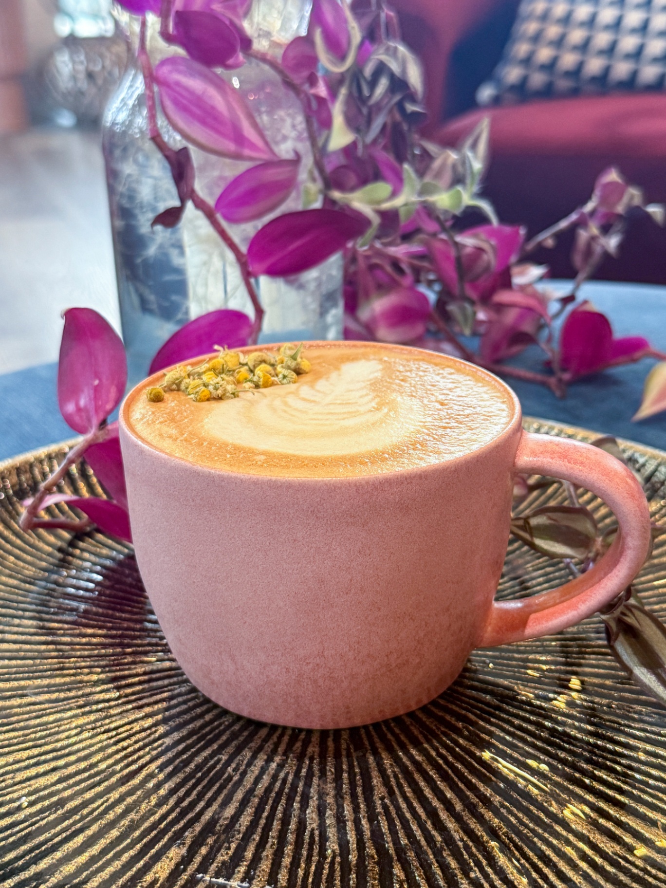 Latte in a pink cup with chamomile garnish