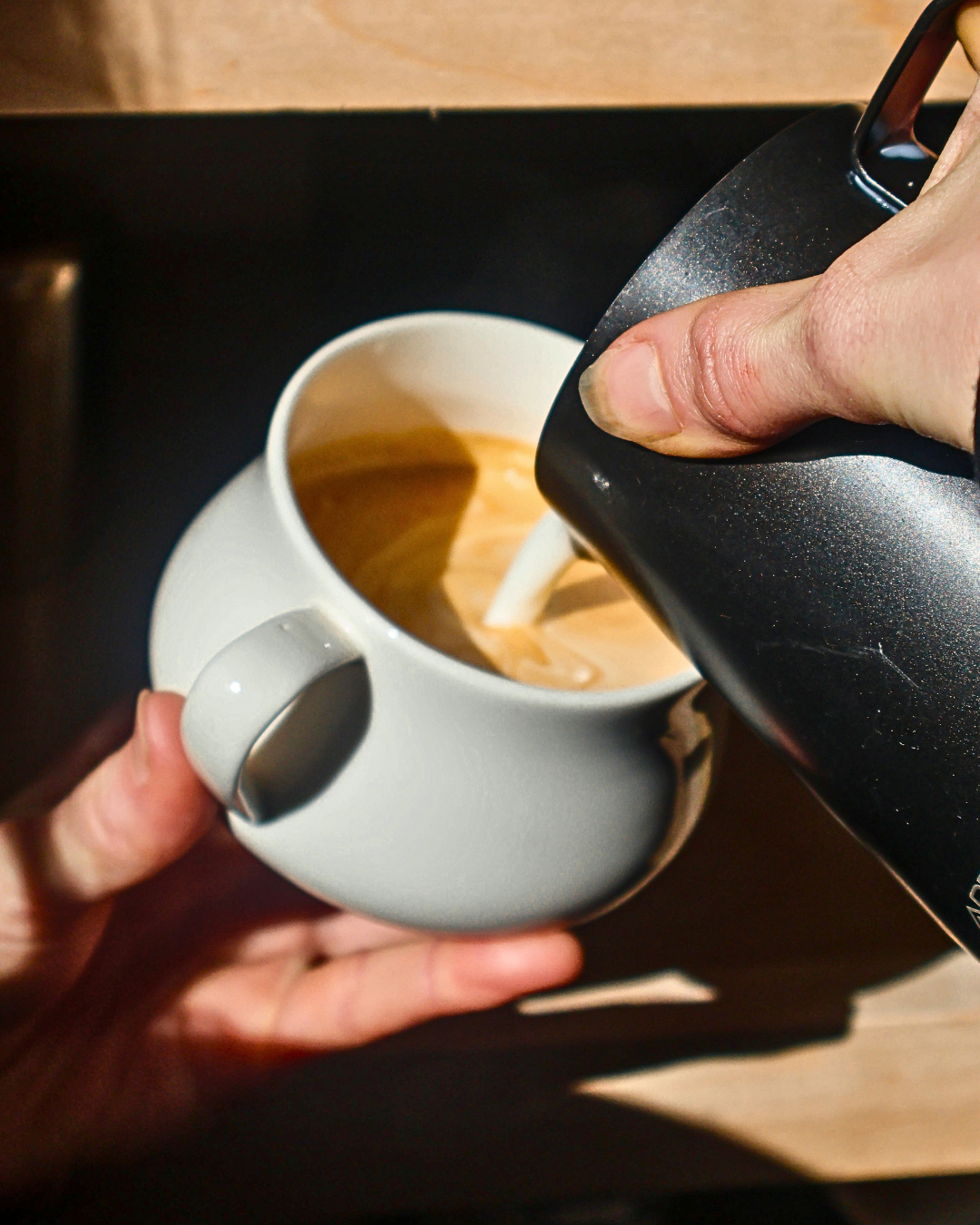 Milk being poured into a ceramic cup