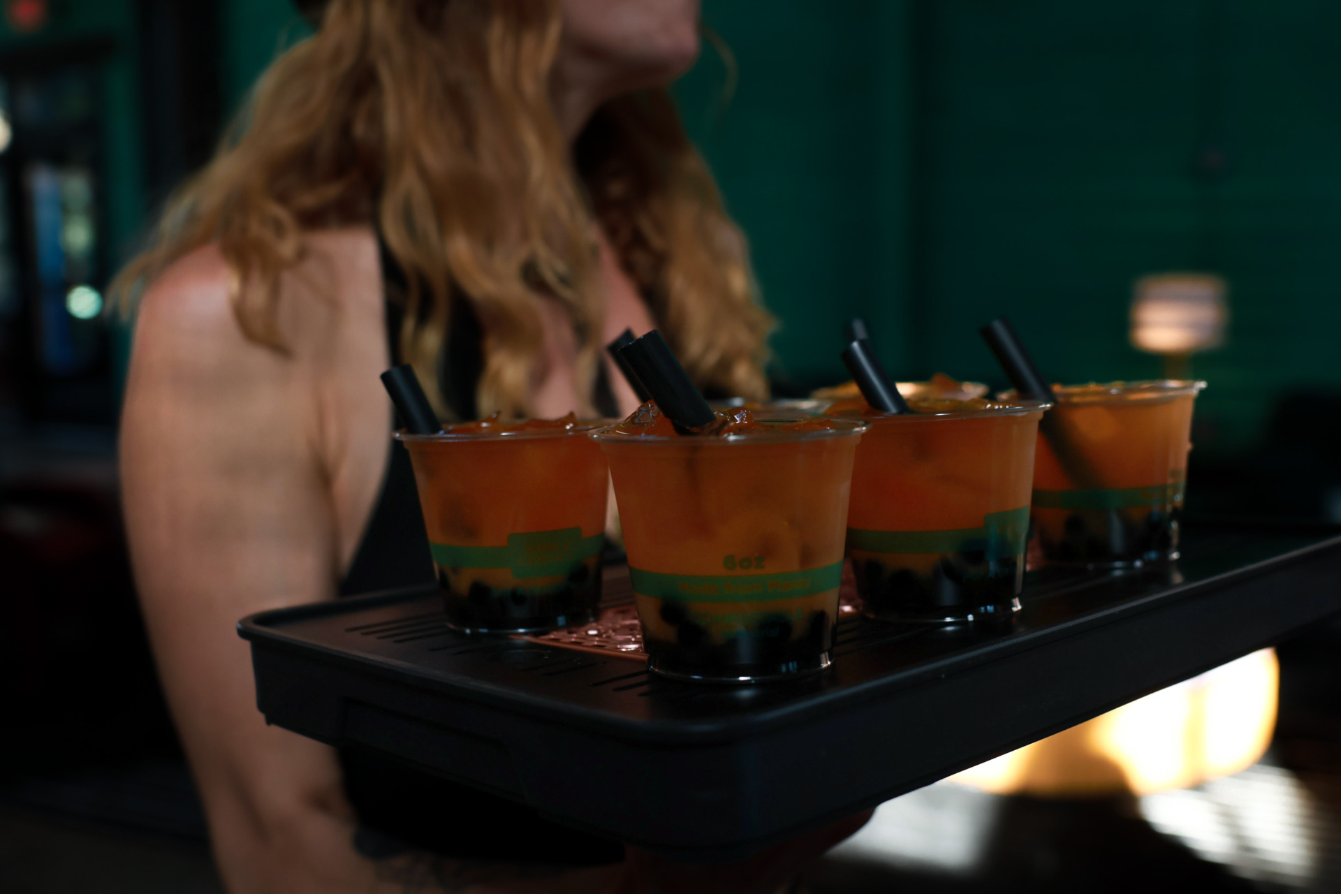 Server at Plant Bar Downtown Asheville carrying a tray of peach black boba tea with tapioca pearls.